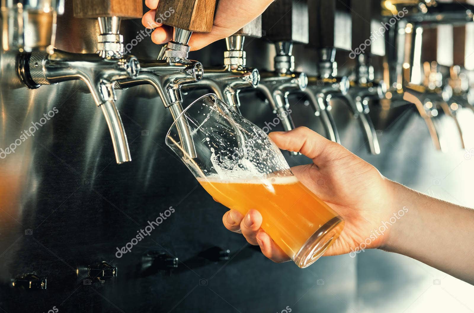 hand of bartender pouring a large lager beer in tap.